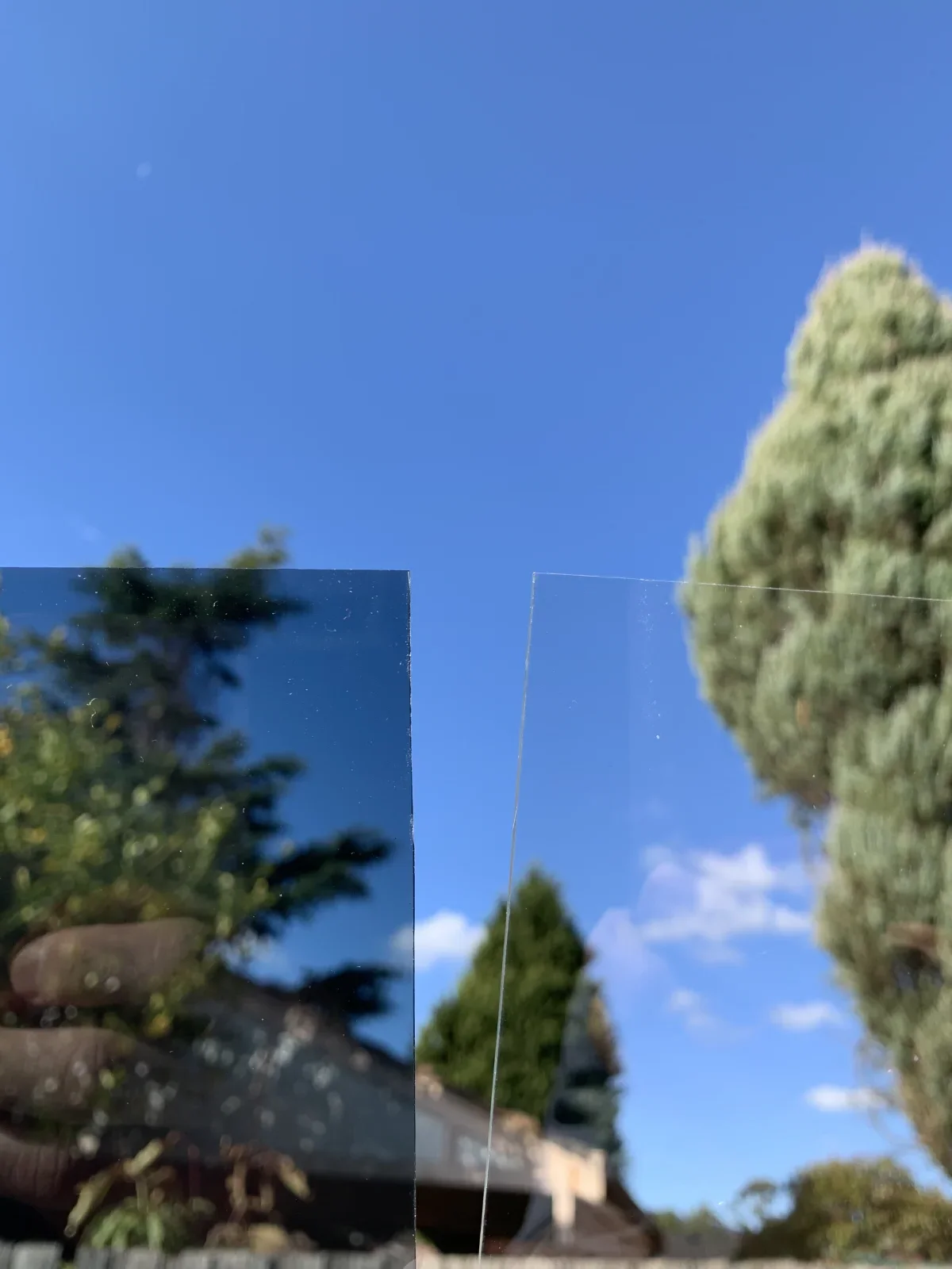 Clear and tinted solid polycarbonate panel samples held against a blue sky